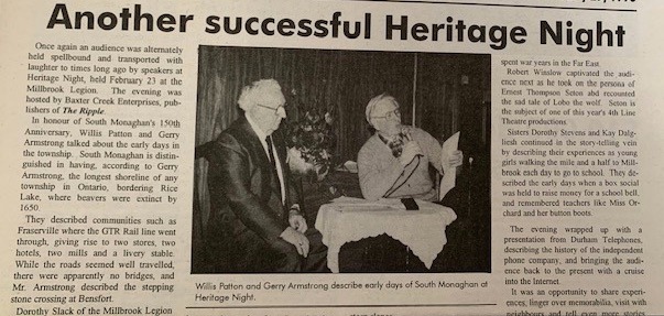 Black-and-white photo of Willis Patton and Gerry Armstrong seated at a small table with microphones during Heritage Night.